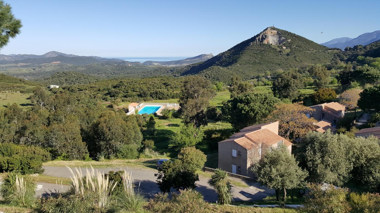 Vue panoramique depuis l’Hôtel & Résidence U Nebbiu en Corse, avec piscine, vallée et golfe de Saint-Florent.