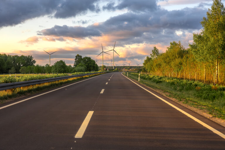 Route à travers la campagne avec éoliennes au coucher du soleil